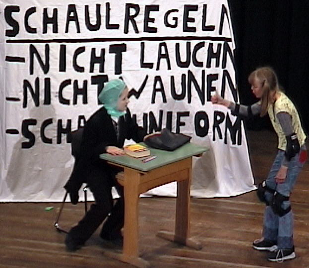Im Hintergrund sind �brigens die tamerischen Schulregeln gro� ausgeh�ngt.